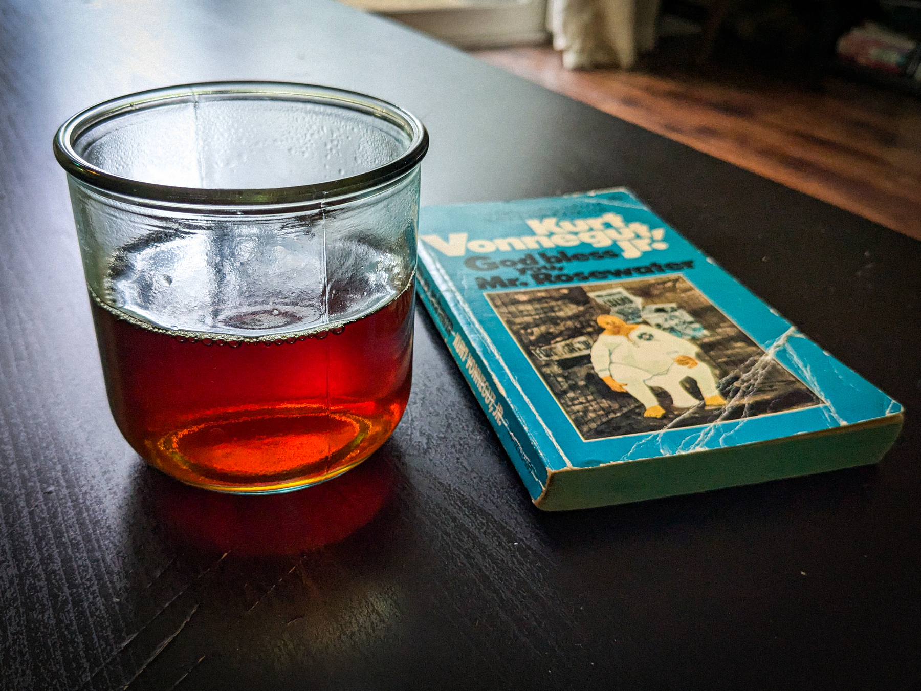 a tea cup and a vintage paperback sit on a coffee table